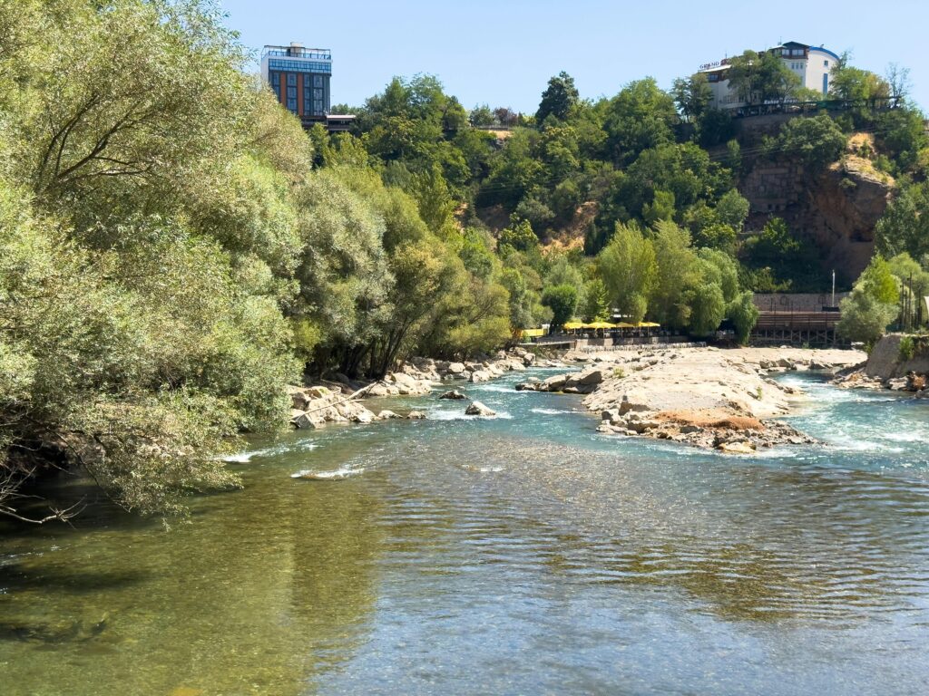 Peaceful river view with lush greenery in Tunceli, Turkey on a sunny day.